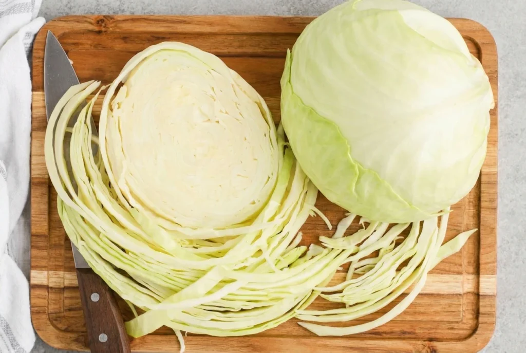cabbage being cut on a wooden board with a knife
